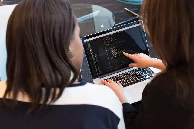 Deux personnes révisent du code ensemble sur un ordinateur portable