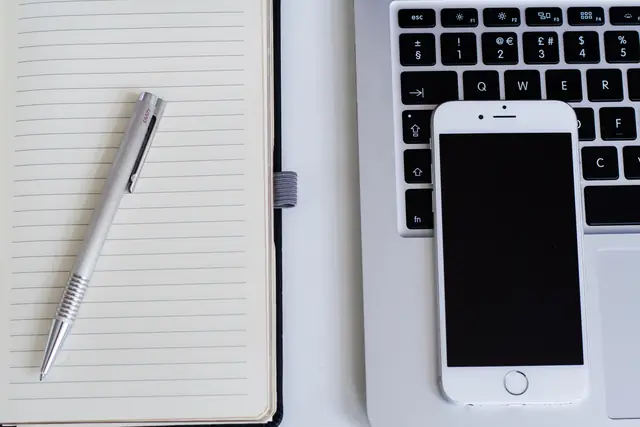 Un ordinateur portable, un téléphone et un carnet sur un bureau